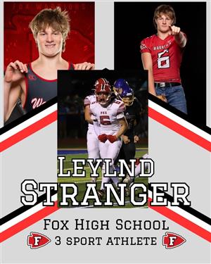 Leylnd Stranger on the football field, wearing a wrestling uniform, and pointing at the camera in his red football jersey.